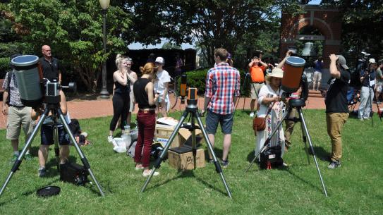 students with telescopes on a lawn