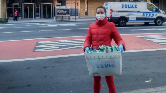 a student wearing a facemask holding a bin of PPE to donate to hospital