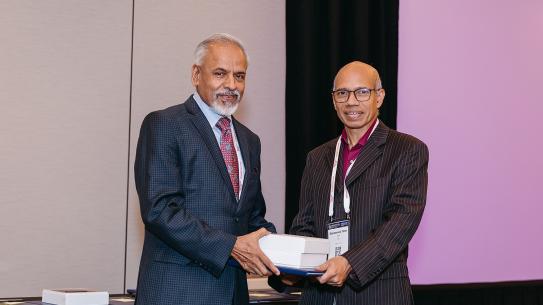 Sreenivasan standing with Dr. Muhammed Taher Saif, holding prize