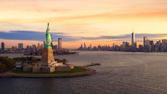 statue of liberty with sunset skyline 