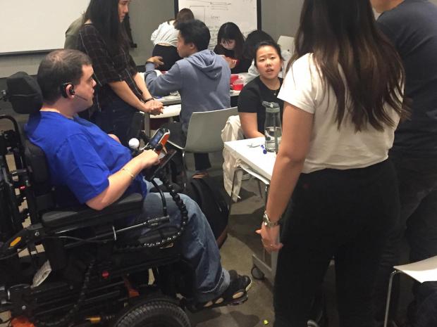 man in wheelchair interacting with students